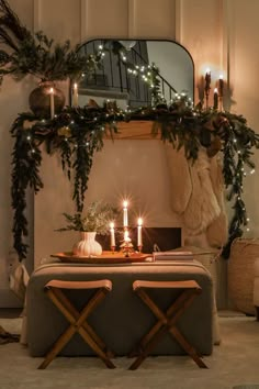 a dining room table with candles and greenery on it in front of a mirror