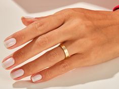 a woman's hand with two gold rings on her left and one red ring on her right