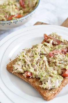 two pieces of toast with guacamole and tomatoes on them sitting on a white plate