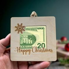 a person holding up a christmas ornament with the words happy christmas on it