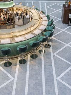 an empty bar with green chairs and stools on the floor in a mall area