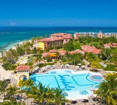 an aerial view of the resort and pool area with palm trees, blue water and white sand