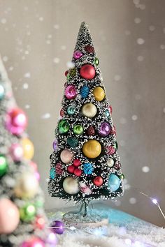 a small christmas tree sitting on top of a table next to a snow covered wall