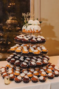 cupcakes are stacked on top of each other in front of a wedding cake