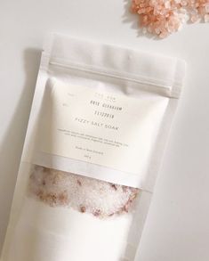 a bag of sea salt sitting on top of a table next to some pink flowers