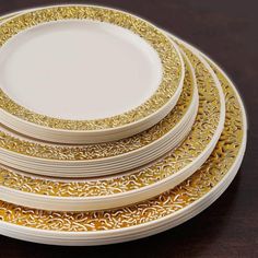 four white and gold plates stacked on top of each other