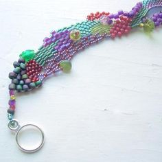 a multi - colored beaded necklace is displayed on a white surface with a pair of scissors