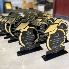 several black and gold graduation trophies sitting on top of a white table with writing on them