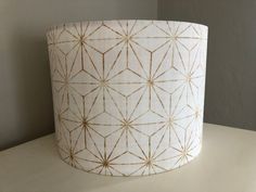 a white lamp shade with gold lines and stars on the bottom, sitting on a table