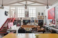 a living room filled with lots of furniture and pictures on the wall next to stairs