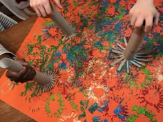 two children are using scissors to cut out paper flowers on an orange sheet of paper