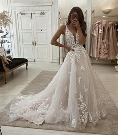 a woman in a wedding dress taking a selfie with her cell phone while looking into the mirror