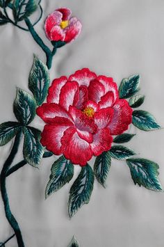 a close up of a flower on a white cloth with green leaves and flowers in the center