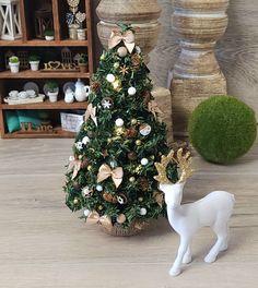 a small christmas tree with a deer figurine next to it