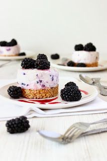 three plates with small desserts on them, one has blackberries and the other has raspberries