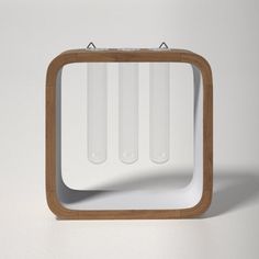 a square wooden object with three glass tubes in it's center on a white surface