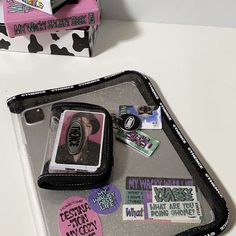 a cell phone sitting on top of a tray next to a box with stickers