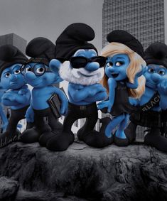 a group of blue cartoon characters standing next to each other on top of a rock