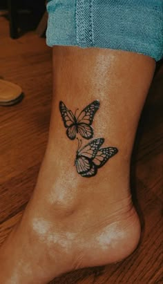 a woman's foot with two butterflies tattoo on the side of her leg,