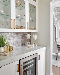 a kitchen with white cabinets and marble counter tops, gold accents on the glass shelves