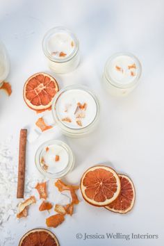 an assortment of orange slices and candles on a white surface with cinnamons scattered around them