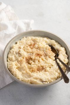 a bowl filled with mashed potatoes on top of a white table cloth next to a spoon