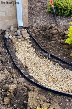 a garden bed with rocks and gravel in front of a brick building