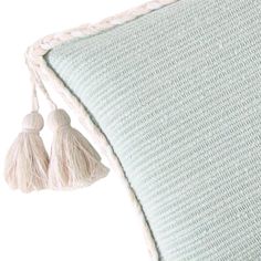 a white pillow with two tassels on the front and back of it's sides