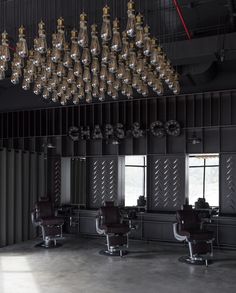 the interior of a hair salon with chandelier and chairs