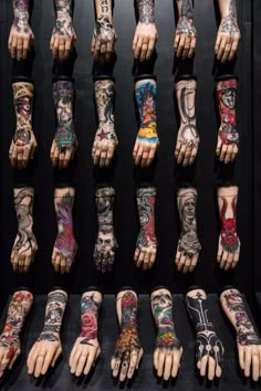 many different colored tattoos on hands and feet are displayed in a display case with black background