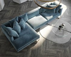 a blue sectional sofa sitting on top of a wooden floor next to a glass table