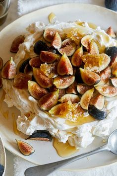 a plate topped with whipped cream and figs on top of it next to silverware