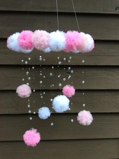 some pink and white pom poms hanging from the side of a wooden building