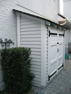 a white building with a black door and some bushes