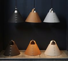 five different colored lamps hanging from the ceiling in a room with black walls and wooden flooring