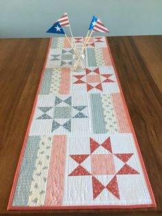 an american flag table runner on a wooden table with two red, white and blue flags