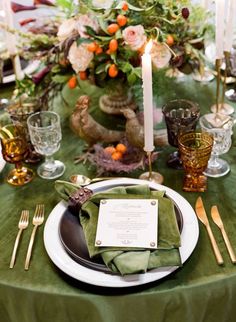 the table is set with green linens and place settings, candles, and flowers