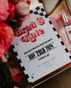 a bottle of perfume sitting on top of a table next to flowers and a sign