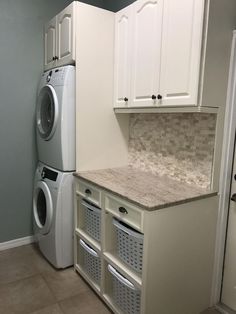 a washer and dryer in a laundry room next to each other with white cabinets