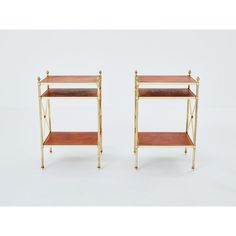 a pair of brass and wood side tables with two shelves on each end, one shelf is