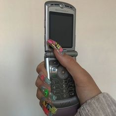 a woman's hand holding up a cell phone with stickers on the screen