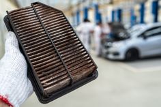 a person holding up a grill in front of a building with cars parked on the street