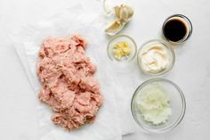 the ingredients to make an appetizer laid out on a white surface, including meat and sauces