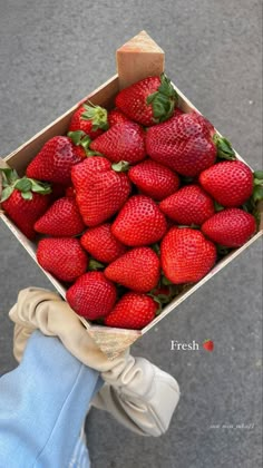 a person holding a box full of strawberries