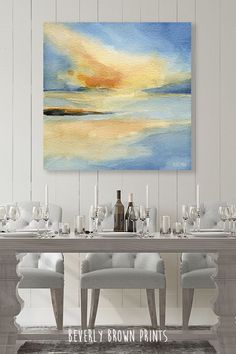 a painting on the wall above a dining room table with white chairs and place settings