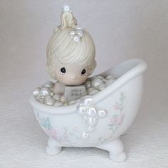 a small figurine sitting in a bathtub filled with pearls