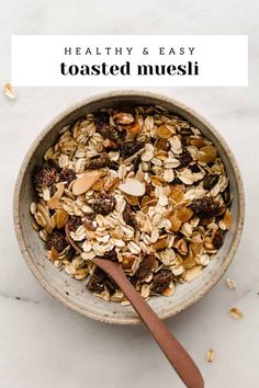 a bowl filled with granola on top of a white counter next to a wooden spoon