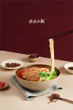 a bowl filled with soup and chopsticks on top of a table next to other bowls