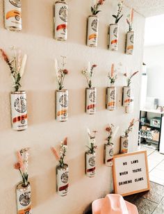 there are many cans on the wall with flowers in them