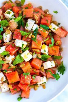 a white bowl filled with watermelon, feta cheese and mint garnish